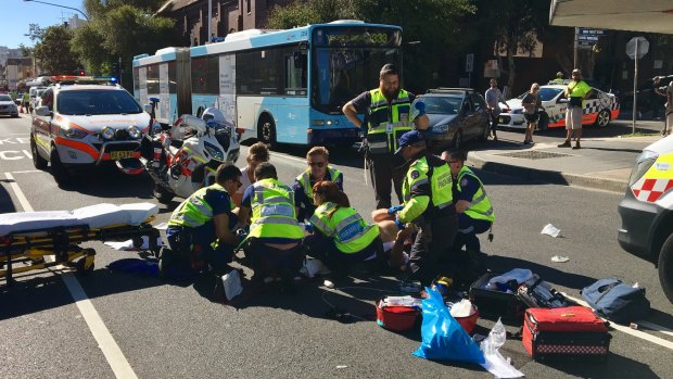 Paramedics attend to a motorbike rider after the collision on Bondi Road.
