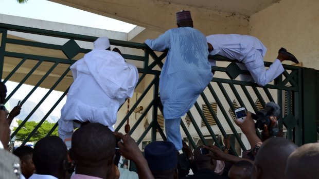 Nigerian Parliament members try to climb the assembly gate to be present for a key security vote. 