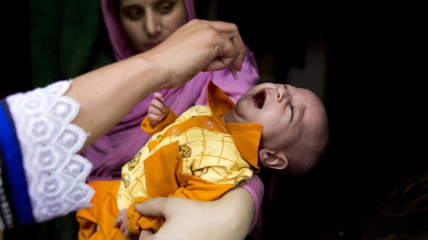 A health worker gives a polio vaccine to a child in Rawalpindi, Pakistan. 