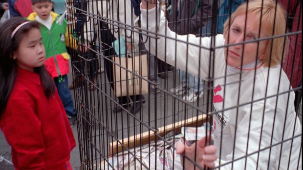 Ingrid Newkirk, president of People for the Ethical Treatment of Animals, sits in a cage at the sprawling Shihlin traditional night market in Taipei in 1998, in protest against the treatment of dogs, which are sold at the market. 