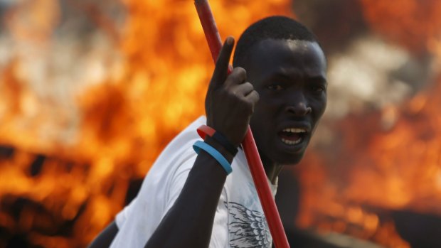 A protester stands in front of a burned barricade during a protest against Burundian President Pierre Nkurunziza's decision to run for a third term in Bujumbura, Burundi on Wednesday.