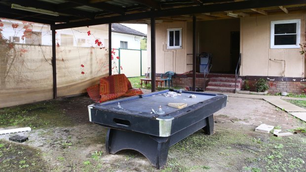 At the back of the house is a navy pool table covered in dirt and strewn with tea bags.