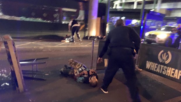 One of the suspects, wearing what appear to be canisters strapped to his chest, lying on the ground after being shot by police outside Borough Market in London.