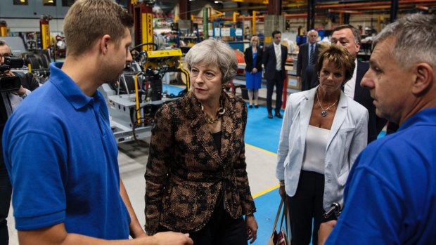PM Theresa May, centre, meets workers during a tour of the bus manufacturer Alexander Dennis in Guildford, England.