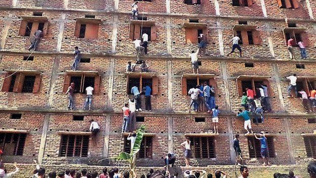 People climb the wall of a building to help students  in an exam in Hajipur, in the Indian state of Bihar. 