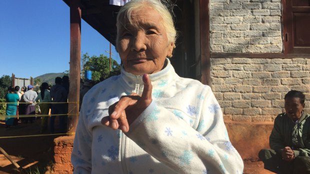 An elderly woman shows her inked finger.