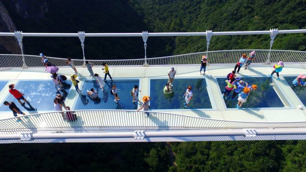 Visitors walk across a glass-floor suspension bridge in Zhangjiajie in southern China's Hunan Province.