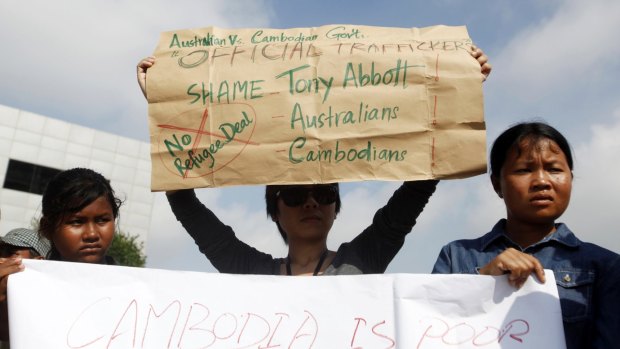 Protesters in Phnom Penh hold signs during a demonstration against Cambodia's plans to resettle intercepted refugees.