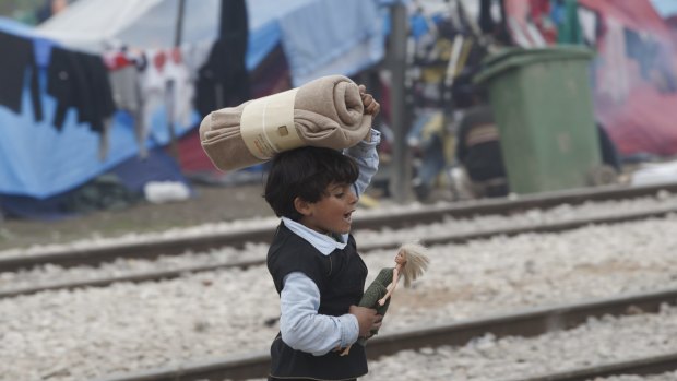A child of a migrant family walks holding a doll in the makeshift refugee camp at the northern Greek border point of Idomeni, Greece, on Thursday.