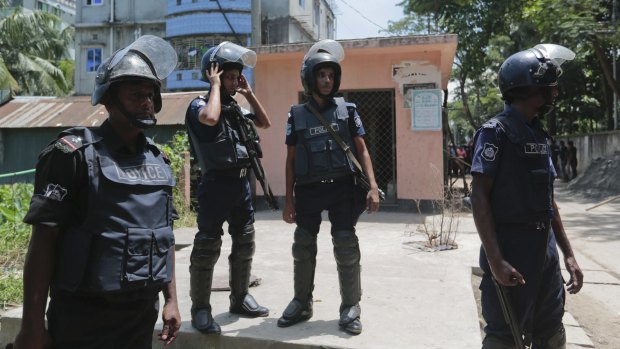 Bangladesh policemen cordon off the area near a two-story house, behind in blue, that they raided in Narayanganj district near Dhaka, Bangladesh.