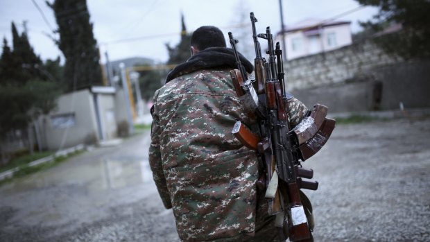 An ethnic Armenian fighter carries Kalashnikov machine guns to his comrade-in-arms at Martakert province in the separatist region of Nagorno-Karabakh on Monday. 