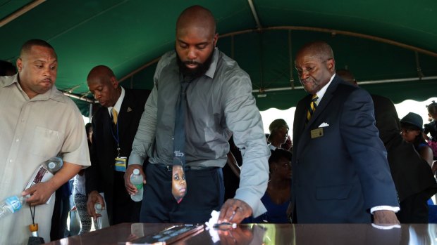 Michael Brown snr wipes the top of the vault containing the casket of his son at his funeral in August.