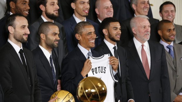 US President Barack Obama holds up a jersey during a ceremony honouring the NBA defending champion San Antonio Spurs at the White House.