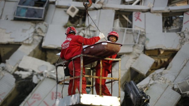 Two emergency workers carry a victim recovered from a collapsed building in Tainan, Taiwan, on Sunday.