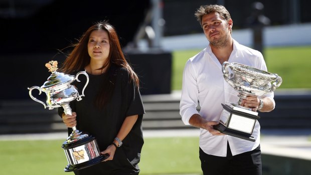 Li Na and and Stanislas Wawrinka carry the men's and women's singles trophies to the official draw at the Rod Laver Arena on Friday.