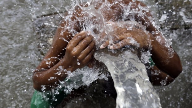 An Indian man bathes in water from a roadside tap in Kolkata, India.