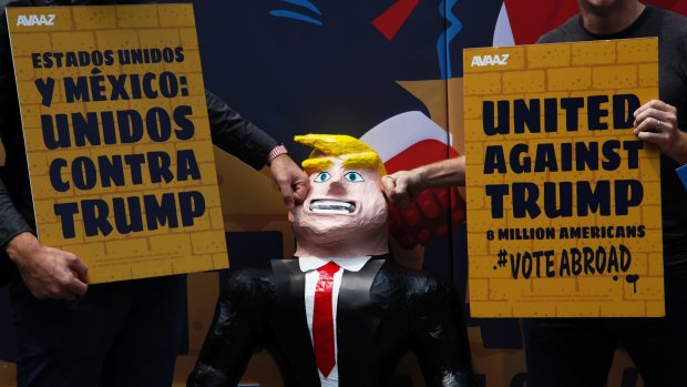 A couple of men hit a pinata representing Donald Trump leaning against a symbolic wall in Mexico City in September.