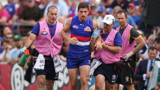 Tom Liberatore is helped off the ground by trainers.