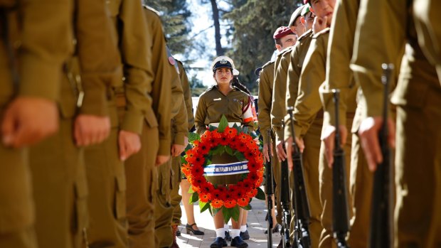 Israeli soldiers stand with wreaths at the funeral.