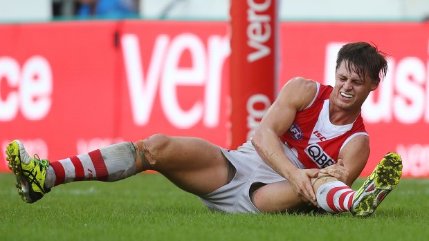Sydney's Callum Sinclair clutches his knee in the dying stages of the Swans' match against the Brisbane Lions at the Gabba. 