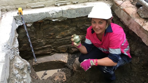 Archaeologist Tina King with a WWII-era bottle found in the test pit at the Harris Terrace.