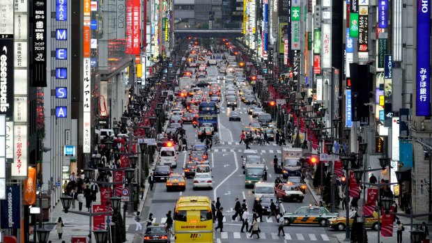 Pedestrians and cars move along the main street of the Ginza district of Tokyo, Japan, 