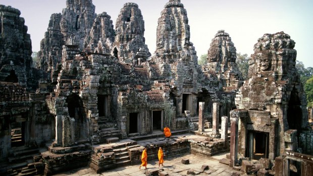 Buddhist monks wander the richly decorated Bayon temple at Angkor.