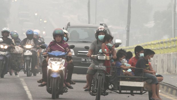 Motorists ride on a road as thick haze from wildfires blankets the city of Pekanbaru, Riau province, Indonesia, earlier this month.