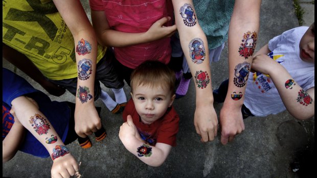 Erik Mosley stands underneath his brothers and sisters who are all wearing temporary tattoos. 
