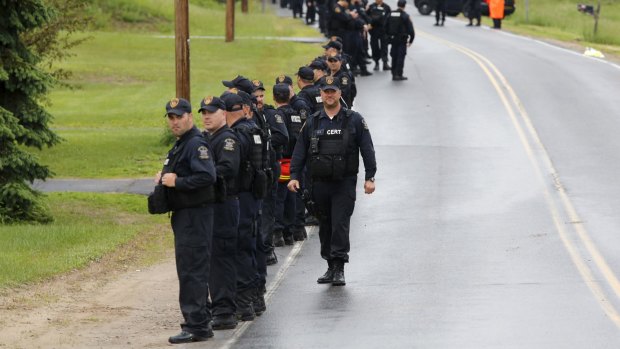 Law enforcement agents line up along a road after emerging from the woods during a search of a wooded area near Cadyville, New York, on Friday.