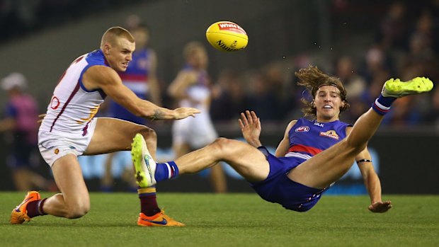 Marcus Bontempelli of the Bulldogs takes a tumble as he is challenged by Mitch Robinson of the Lions.