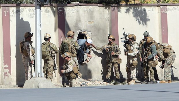 Afghan security personnel rescue a man from the Shamshad TV compound.