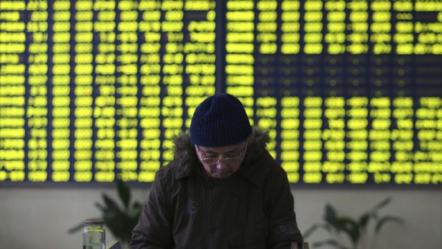 A stock investor pauses near a display board showing stock prices in green to symbolise a fall in price at a brokerage house in Jiujiang in central China's Jiangxi province.