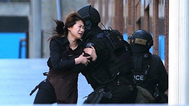 One of the women held hostage inside the cafe for several hours runs into the arms of police after being freed. 