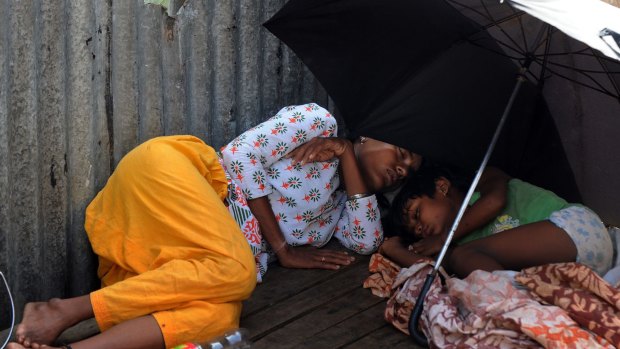 An Indian woman and child sleep under an umbrella at the roadside in Kolkata.