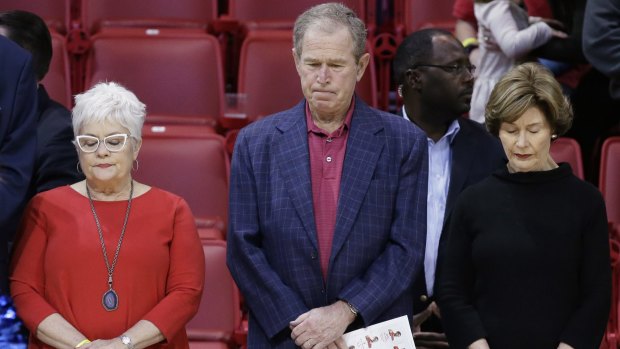 Former president George W Bush observes a moment of silence with his wife, Laura Bush (right), and others in support of the victims of the Paris terrorist attacks, before a college basketball game.