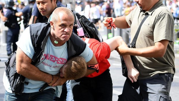 A man is subdued by a policemen in plain clothes during clashes between English and Russian supporters in the Old Port of Marseille.
