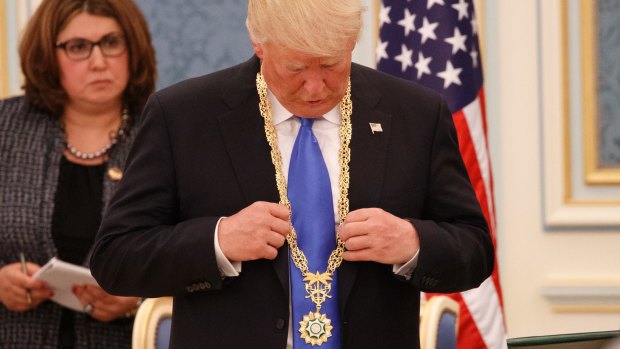 US President Donald Trump looks at the Collar of Abdulaziz Medal after receiving it.