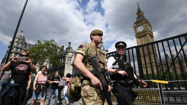 An armed soldier and a police officer patrol outside the Houses of Parliament in London.
