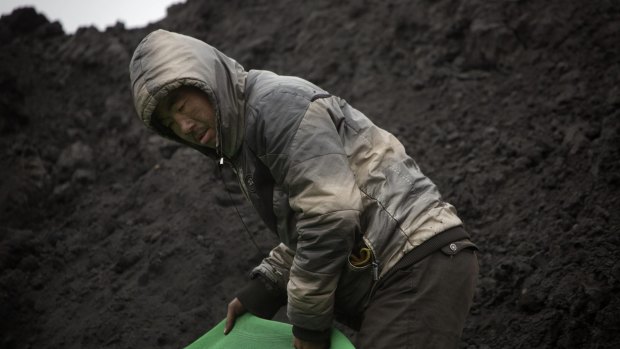 A worker pulls protective fabric over a pile of coal at a shuttered coal mine near Ordos in northern China's Inner Mongolia Autonomous Region last year.