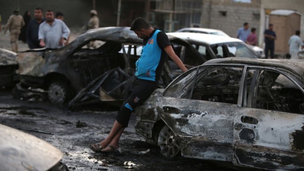 Cycle of violence: Iraqi men gather at the scene of one of the two car bombs that exploded in Baghdad's Habibiyah area in May 2013.