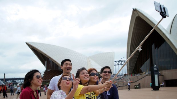 Happy snap: Audrey Amparo uses a selfie stick to photograph her family at the Opera House.