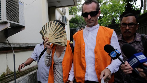 Sarah Connor covers her face with a fan as she and David Taylor arrive at Denpasar District Court on Wednesday.