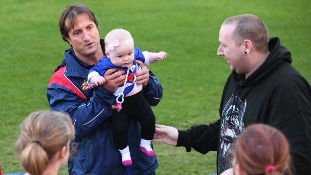 Bulldogs head coach Luke Beveridge poses with a baby during a training session at Whitten Oval on Tuesday.