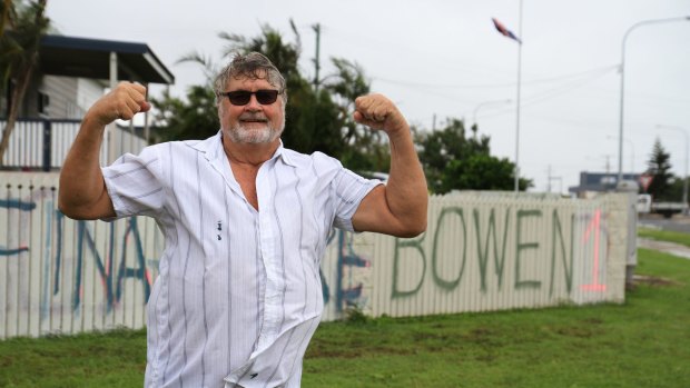 Graham Wilson of Bowen paints a fresh message on his fence in the wake of Cyclone Debbie.