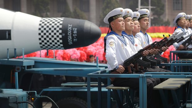 Navy personnel sit in front of a submarine-launched "Pukguksong" ballistic missile as it is paraded through Pyongyang, North Korea.