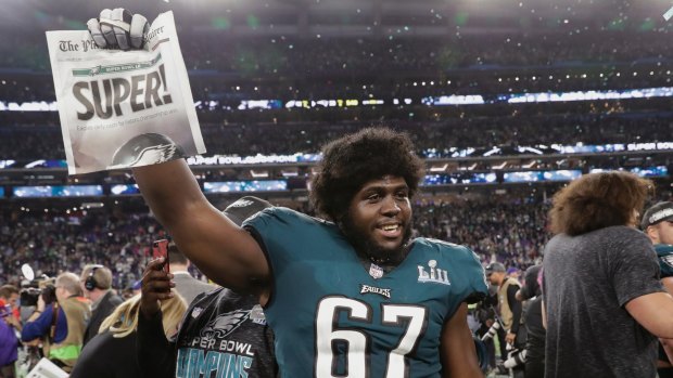 Eagles offensive guard Chance Warmack holds up a newspaper.