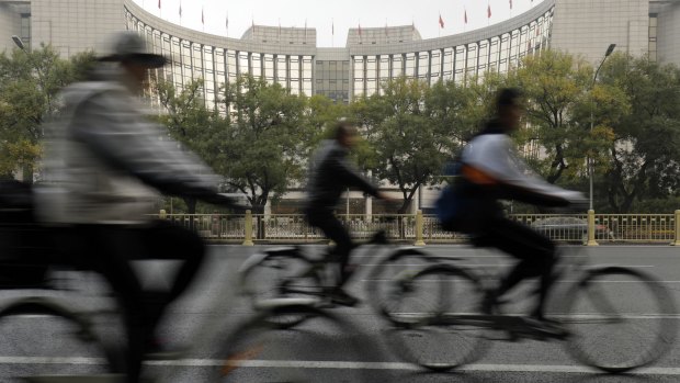 Cyclists ride past the People's Bank of China headquarters in Beijing on Thursday.