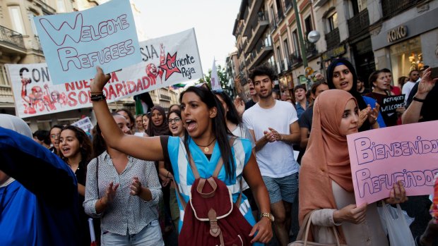 Protesters shout slogans as they hold placards welcoming refugees during a show of solidarity and support for refugees in Madrid, Spain.