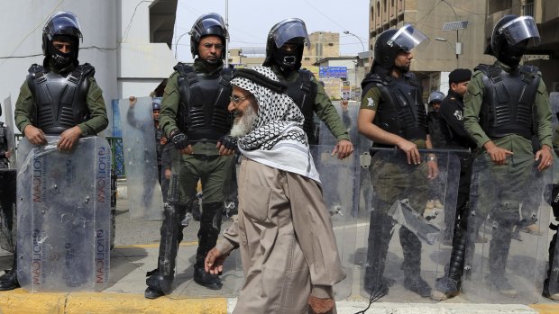 A protester passes riot police guarding the heavily fortified Green Zone in Baghdad on Friday.